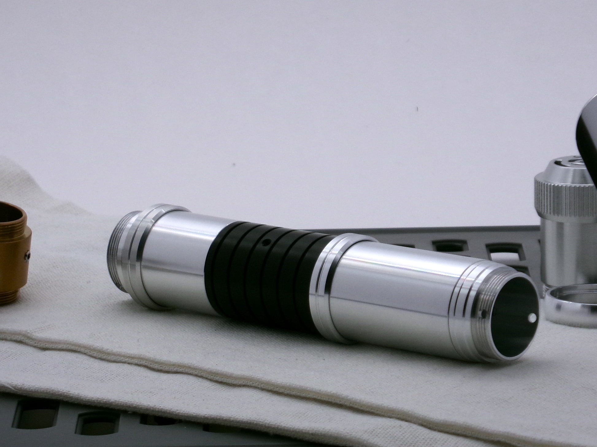 Single aluminum female/female threaded body component installed above a black VHC lightsaber extension adorned with an accent ring; three-quarter view.