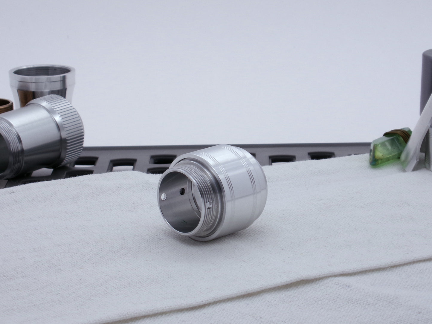 Assembled Pommel Assembly Kit for VHC lightsabers, sitting on cloth among lightsaber parts, three quarter view top.