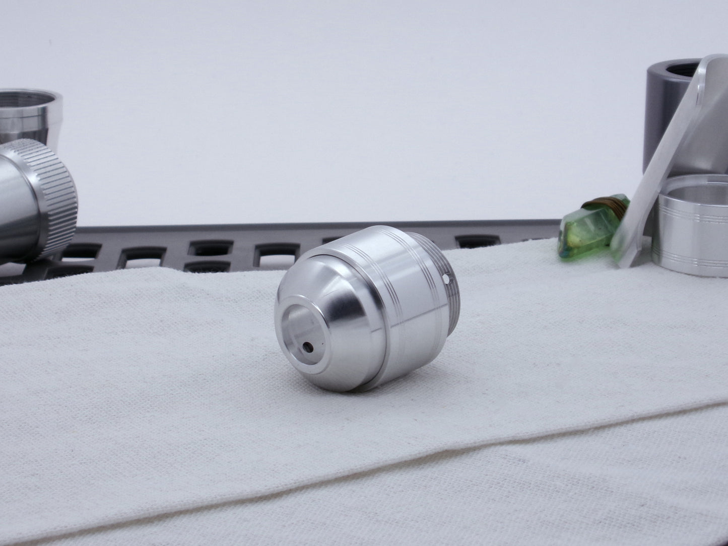 Assembled Pommel Assembly Kit for VHC lightsabers, sitting on cloth among lightsaber parts, three quarter view bottom.