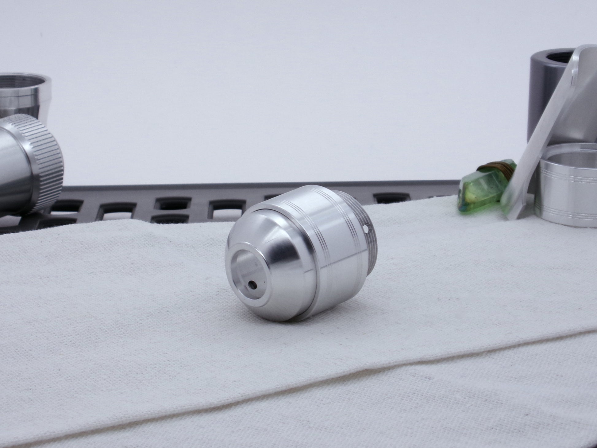 Assembled Pommel Assembly Kit for VHC lightsabers, sitting on cloth among lightsaber parts, three quarter view bottom.