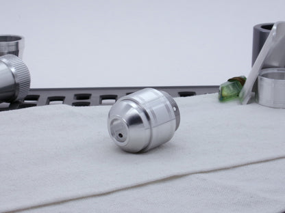 Assembled Pommel Assembly Kit for VHC lightsabers, sitting on cloth among lightsaber parts, three quarter view bottom.