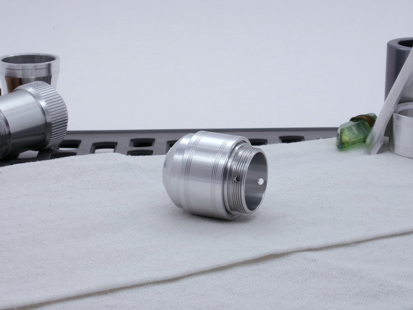 Assembled Pommel Assembly Kit for VHC lightsabers, sitting on cloth among lightsaber parts, three quarter view bottom.