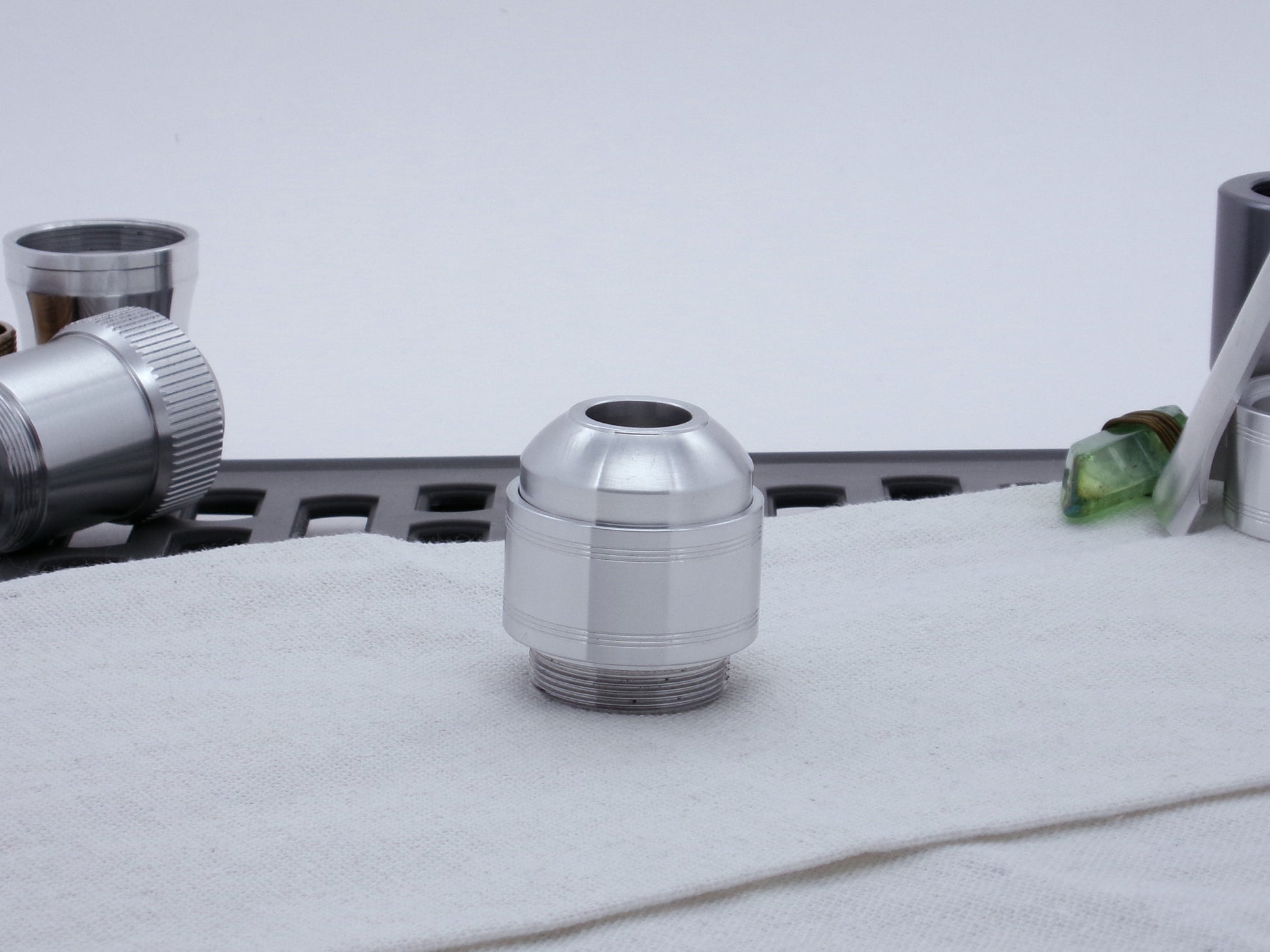 Assembled Pommel Assembly Kit for VHC lightsabers, sitting vertically on cloth among lightsaber parts.