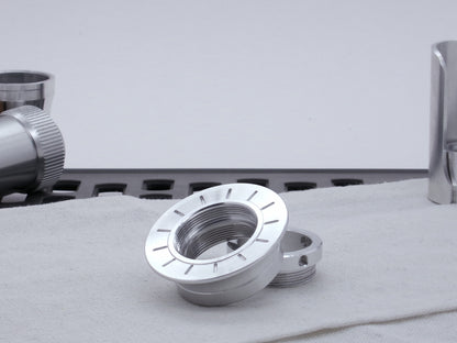 A VHC compatible lightsaber Emitter Flange askew atop an Emitter Tip, resting on cloth among lightsaber parts.