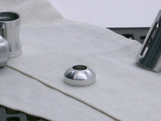 A basic, aluminum female-threaded pommel.  Shows rounded profile and single sound exit hole lying flat.